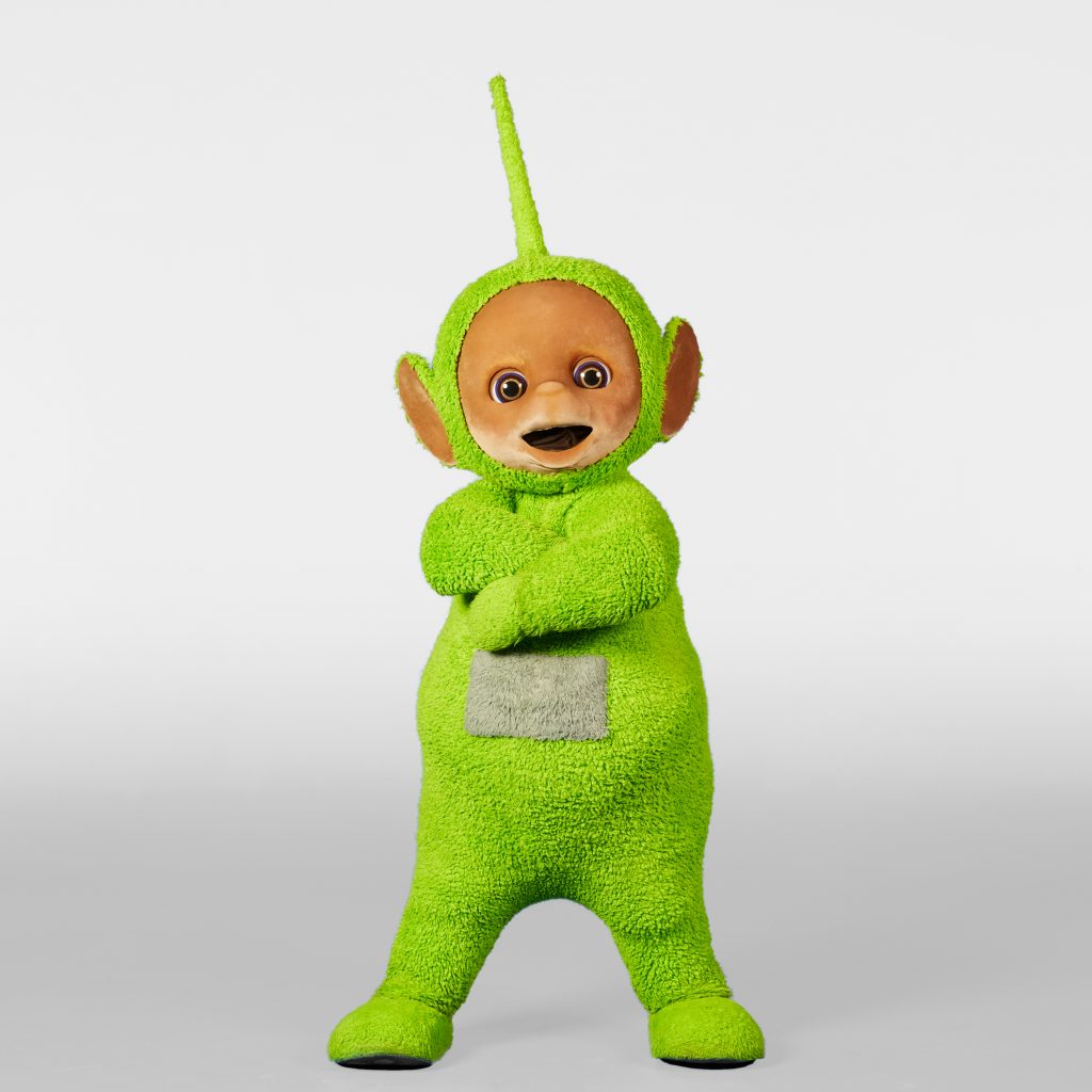 Dipsy is posing in a white studio with arms folded. 